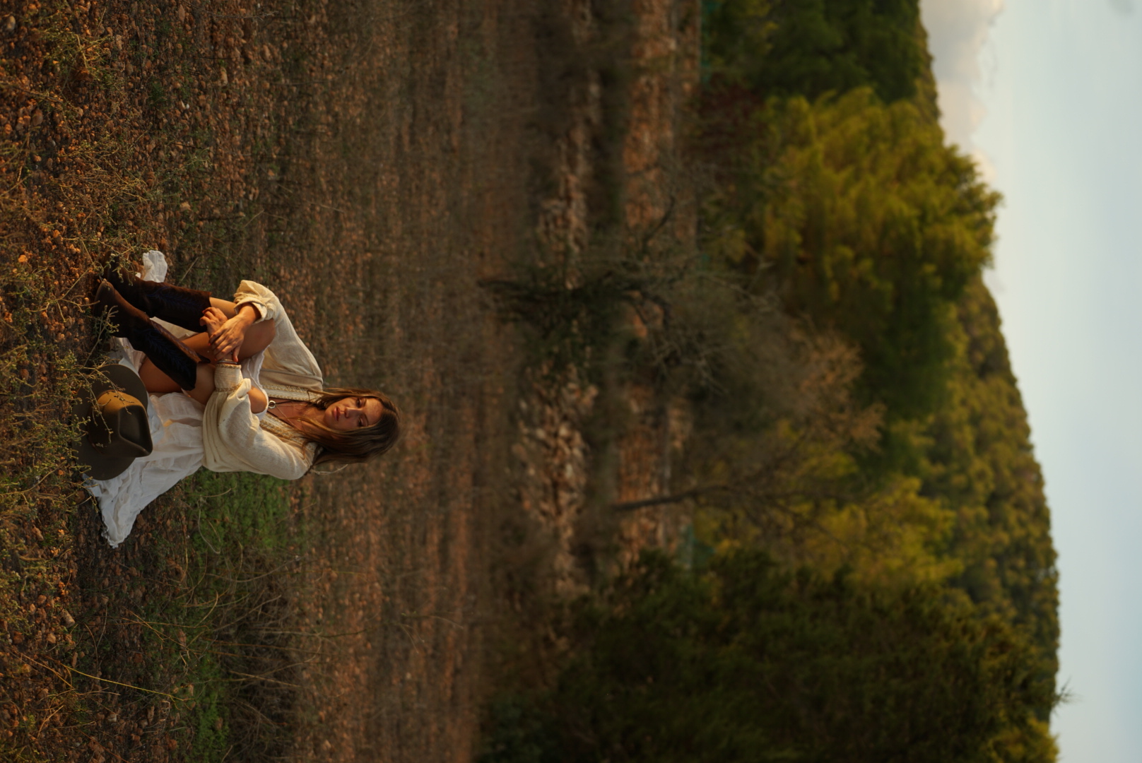Talia in a flowing white dress, arms open in a golden field at sunset